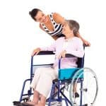 Auxiliaire de vie poussant une personnes en fauteuil roulant
